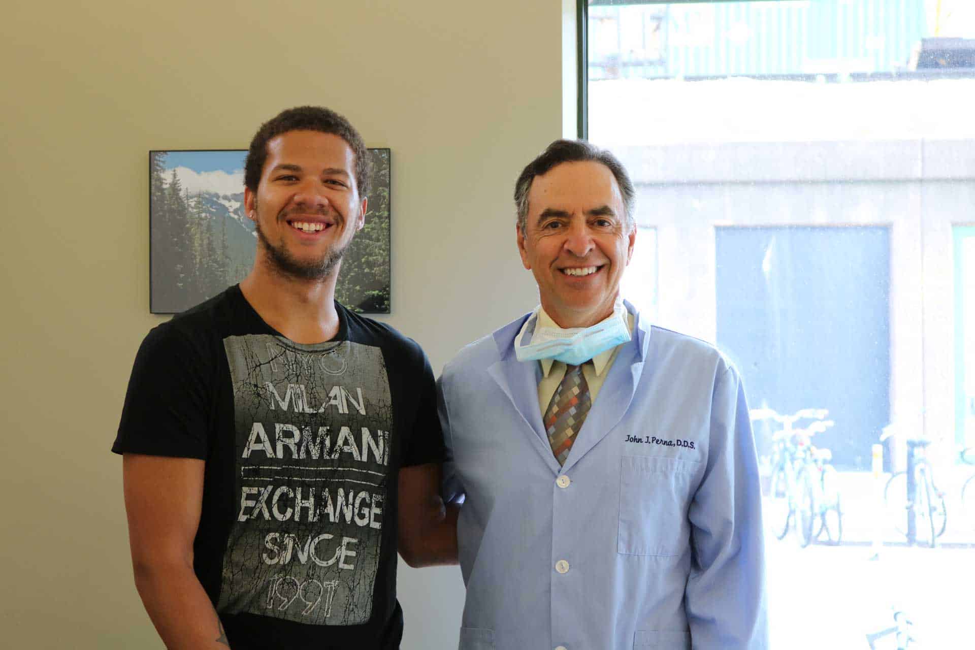 Dr John Perna standing side by side with smiling patient.
